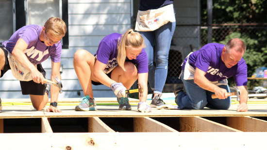 President Pietruszkiewicz and UE students hammer nails into a floorboard