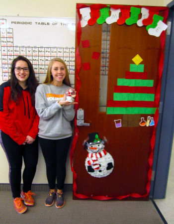 Chemistry students Lauren Roberts and Maegen Kincanon standing by Christmas decorated door.