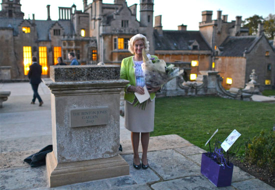 Margaret, Lady Benton Jones stand by the Benton Jones monument with flowers.