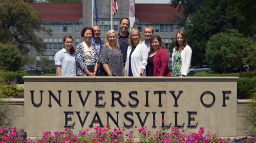 New faculty members standing in front of the UE sign.