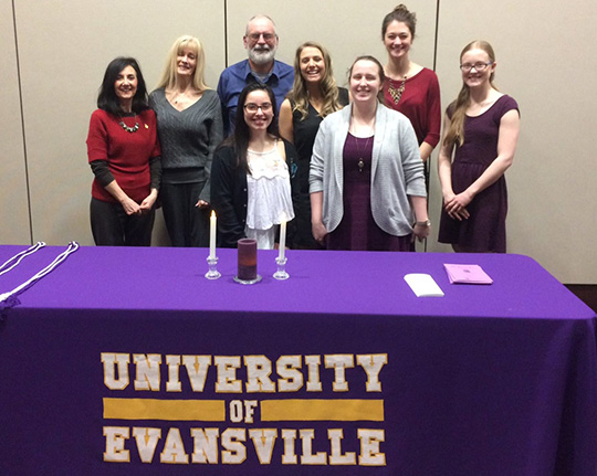 New members of Phi Sigma Iota standing in front of table.