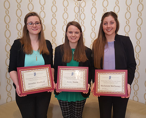 Three girls holding awards