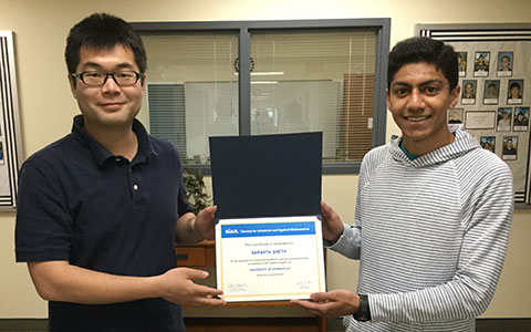 Two students holding an award