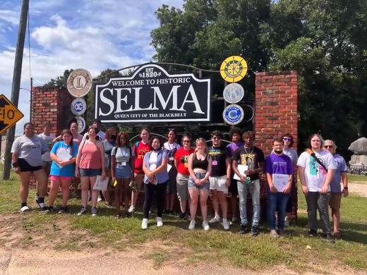 Many students standing in front of a sign.