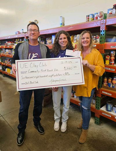 Alayna Acree, President of UE Clay Club, and Professor Todd Matteson, Advisor to UE Clay Club, present a check to Amanda Drew, Community Food Bank, in the sum of $6880.00.
