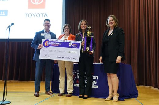 Student and administrators holding a check and trophy